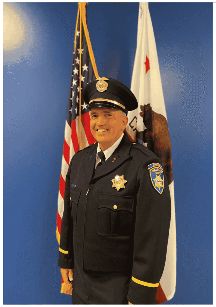 SPD Chaplain Bosic standing in front of department flags for an official portrait.